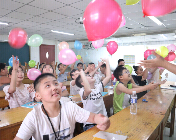 图为学生们在游戏中开心地向空中抛起气球,随着气球的飘动而欢呼雀跃.